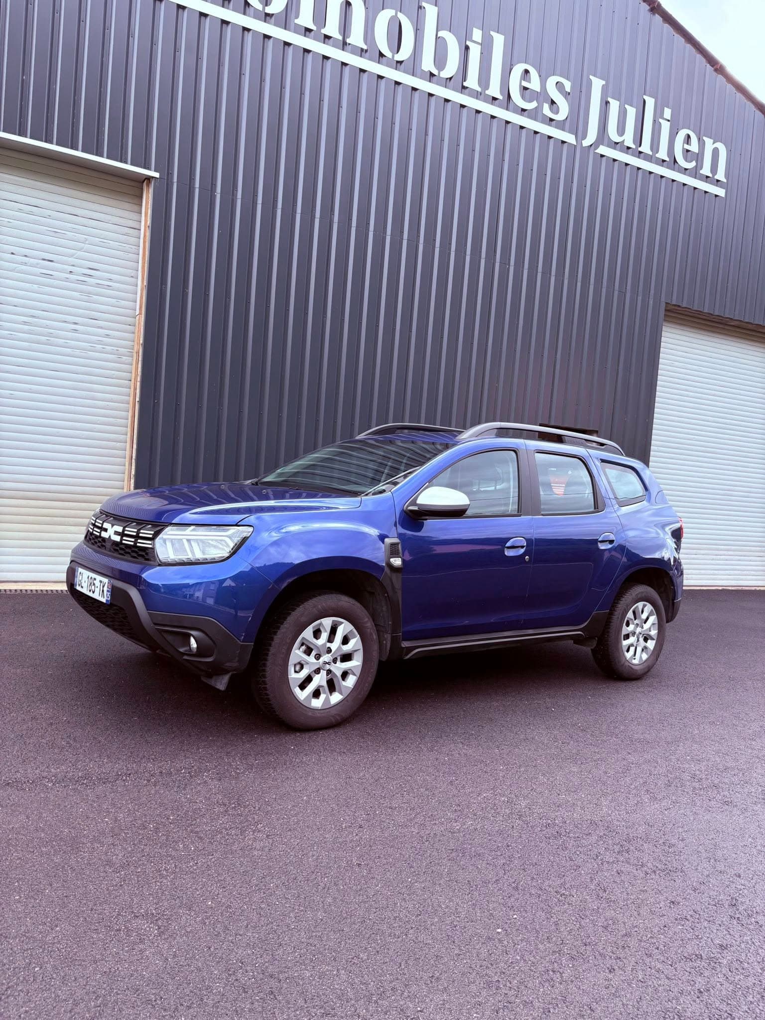 Dacia Duster bleu devant le garage