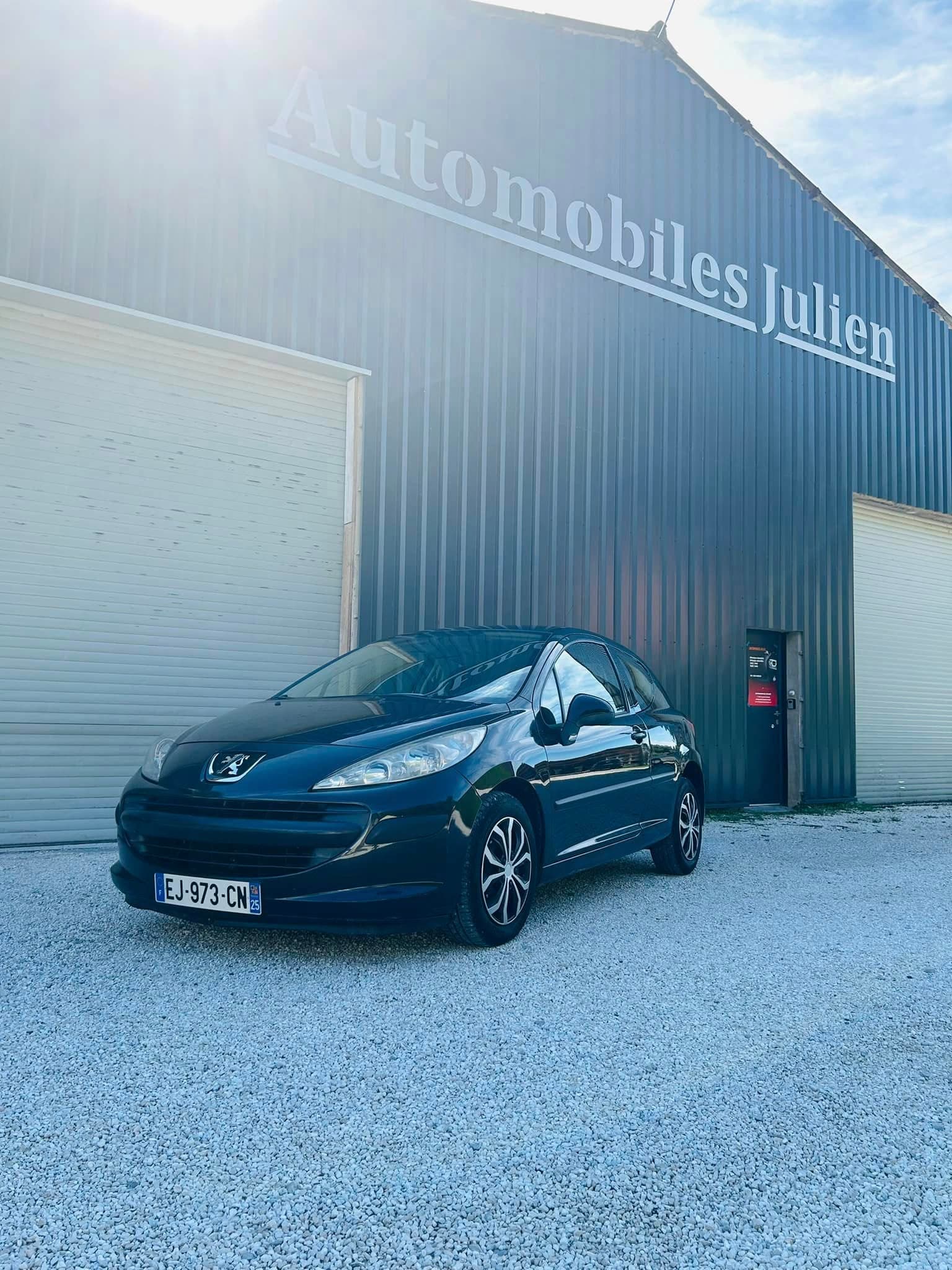 Peugeot 207 noire devant le garage